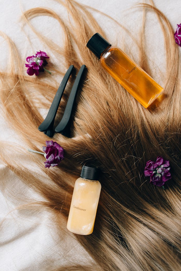 about-us-01 Aesthetic flatlay of hair care items and flowers against a soft background.